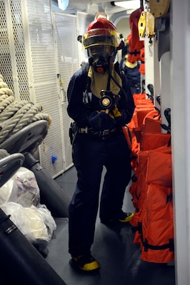 Megan Green retreats from a space after a simulated fire is put out during a damage control training drill aboard the Arleigh Burke-class guided-missile destroyer USS William P. Lawrence (DDG 110)