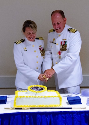 Woman and man in their white uniform cutting the cake