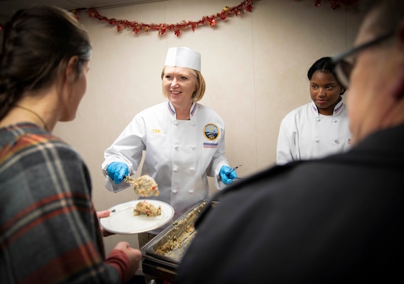 Woman in her white chef uniform serving food to guests