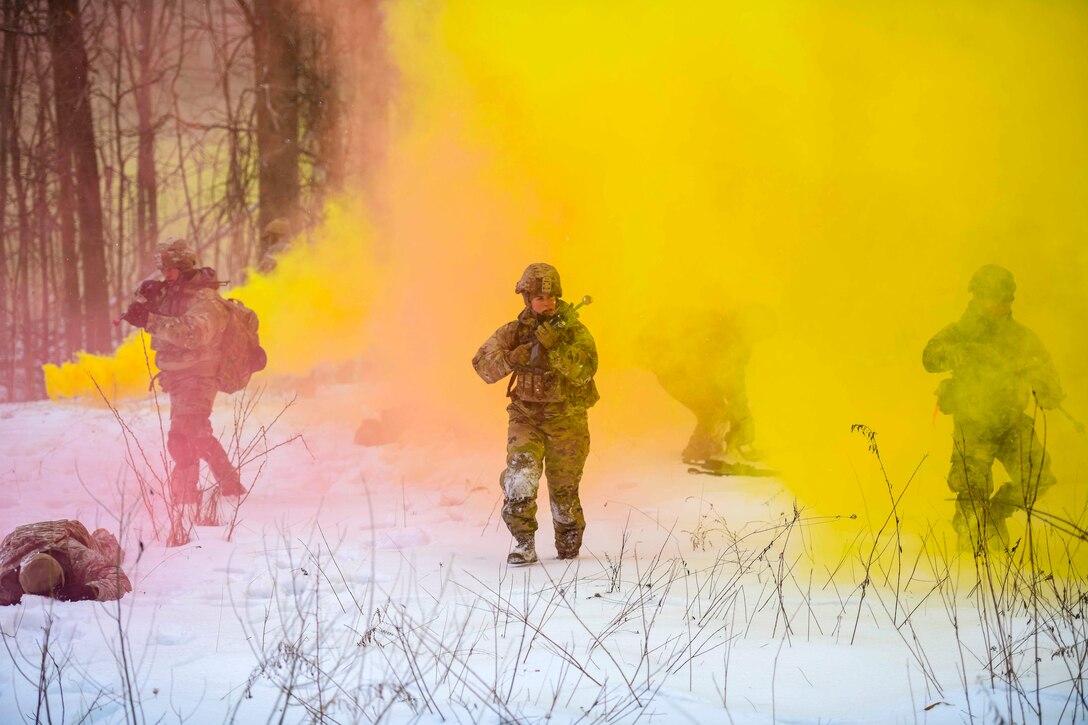 Airmen walk through red and yellow smoke.