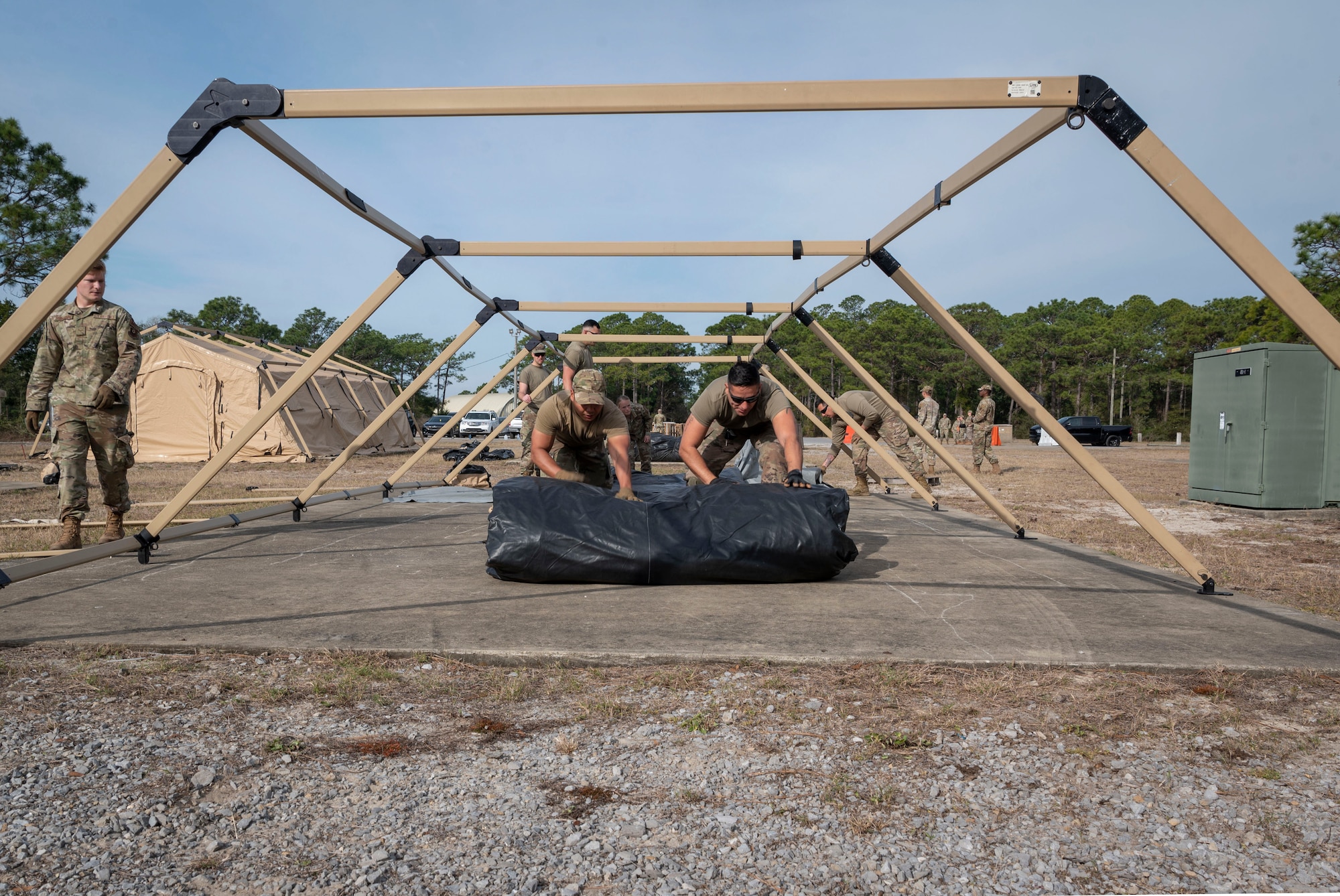 U.S. Air Force Staff Sgt. Merlin Abril, left, and U.S. Air Force Senior Airman Diego CalleCalle, right, 1st Special Operations Civil Engineer Squadron Mission Sustainment Team members, roll out a military shelter system during a MST training March 3, 2022, at Hurlburt Field, Florida.