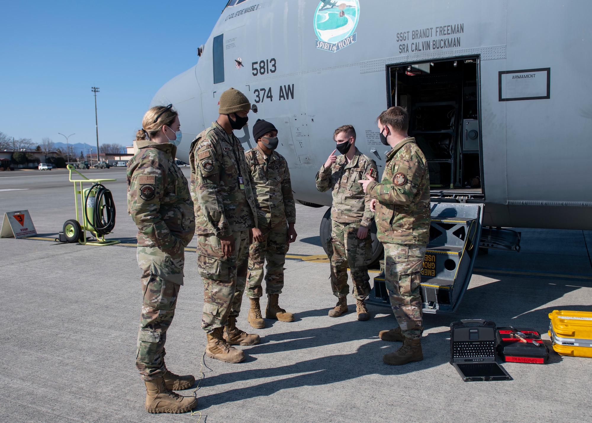 Maintenance airmen talk over the work they're about to perform on a military cargo plane.