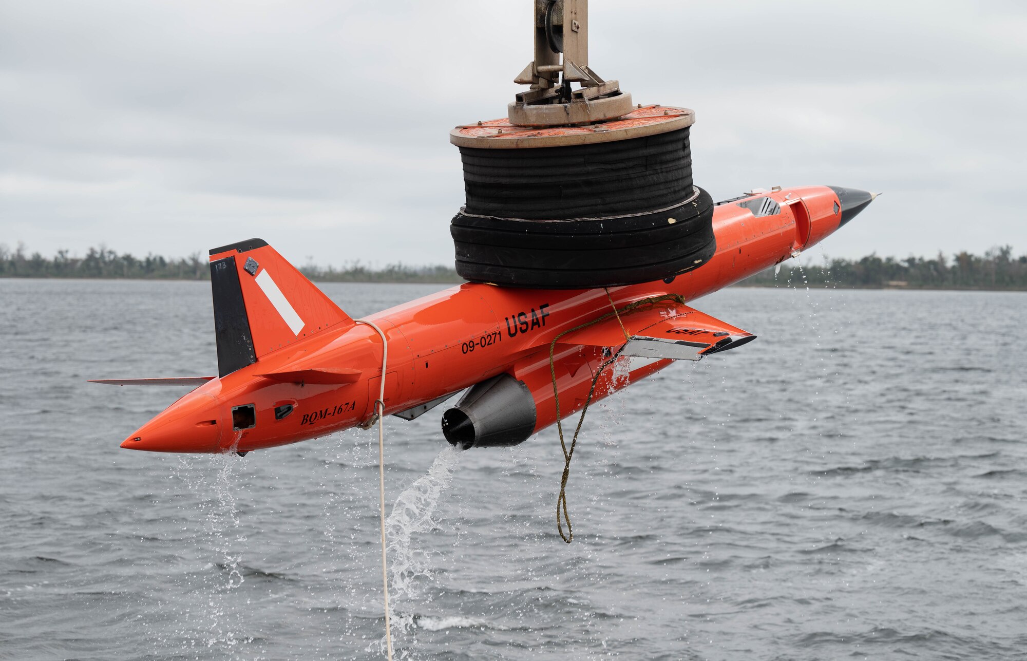 A subscale drone is pulled out of water by a crane.