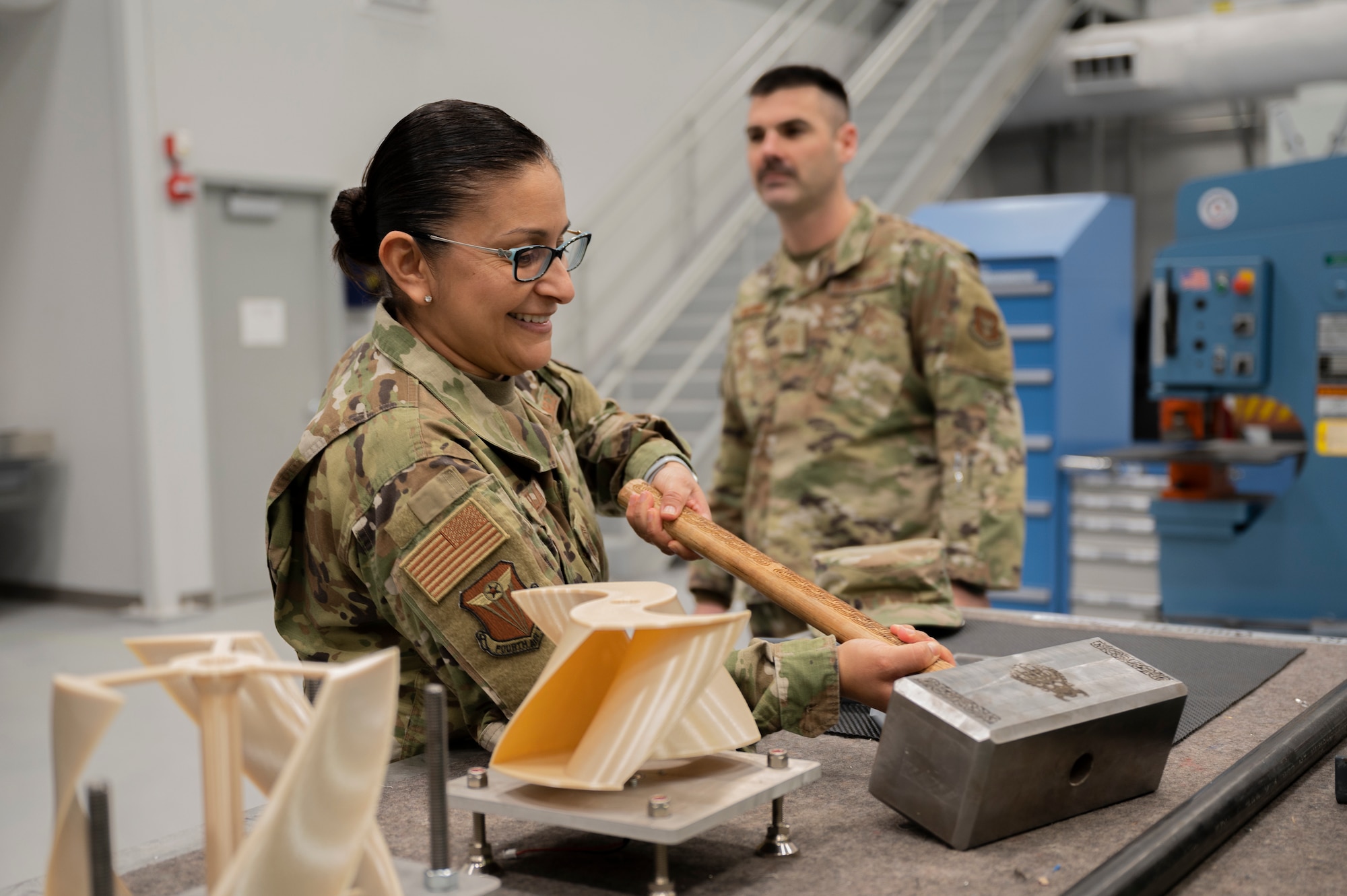 Chief Master Sgt. Cynthia Villa, 4th Air Force command chief, picks up a hammer with Senior Master Sgt. Justin Decroo, 911th Maintenance Squadron fabrication flight superintendent, at the Pittsburgh International Airport Air Reserve Station, Pennsylvania, March 5, 2022.