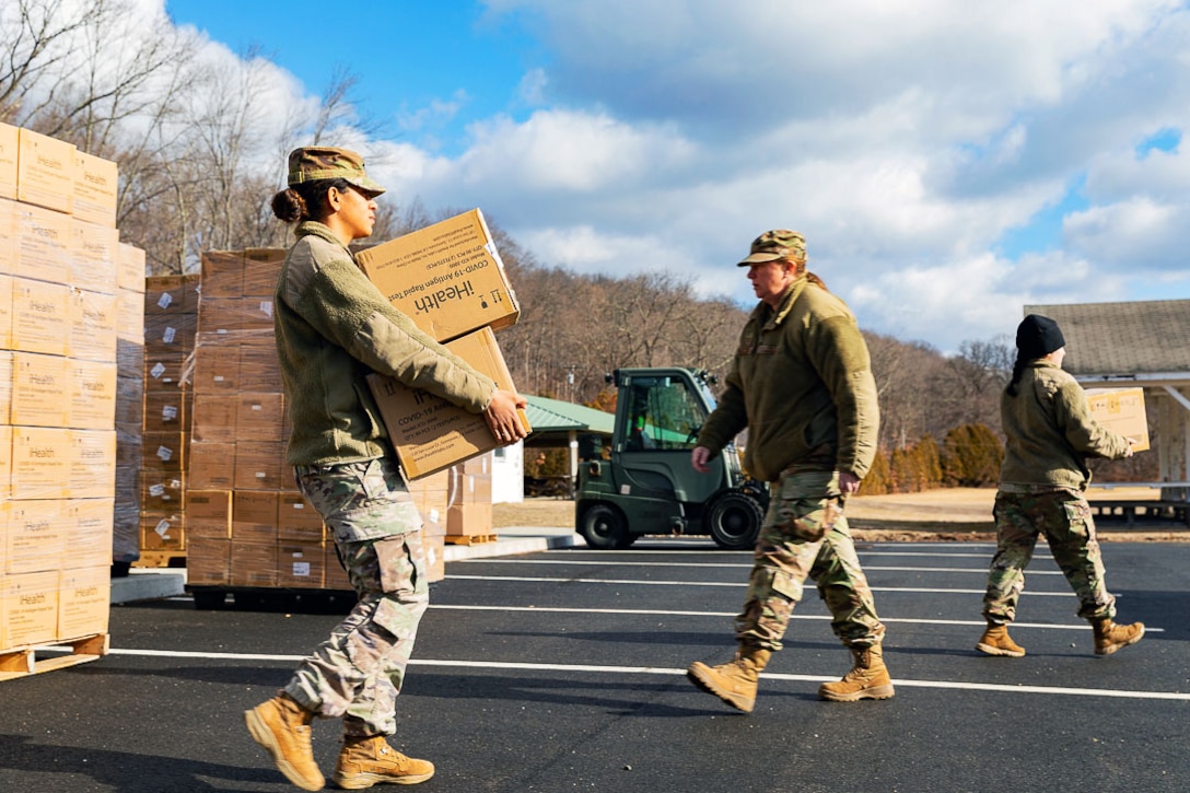 Soldiers carry boxes of COVID-19 relief supplies.
