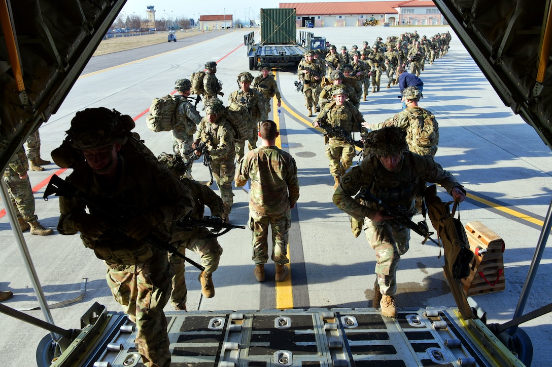 Soldiers line up to board a plane.