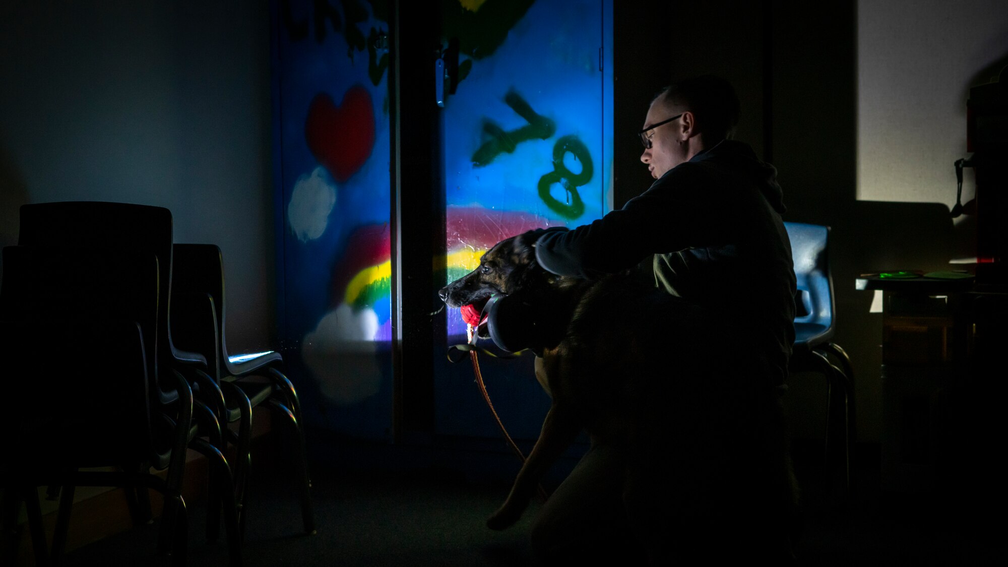Military working dog trainer rewards his MWD with a toy as they search the building for simulated explosives