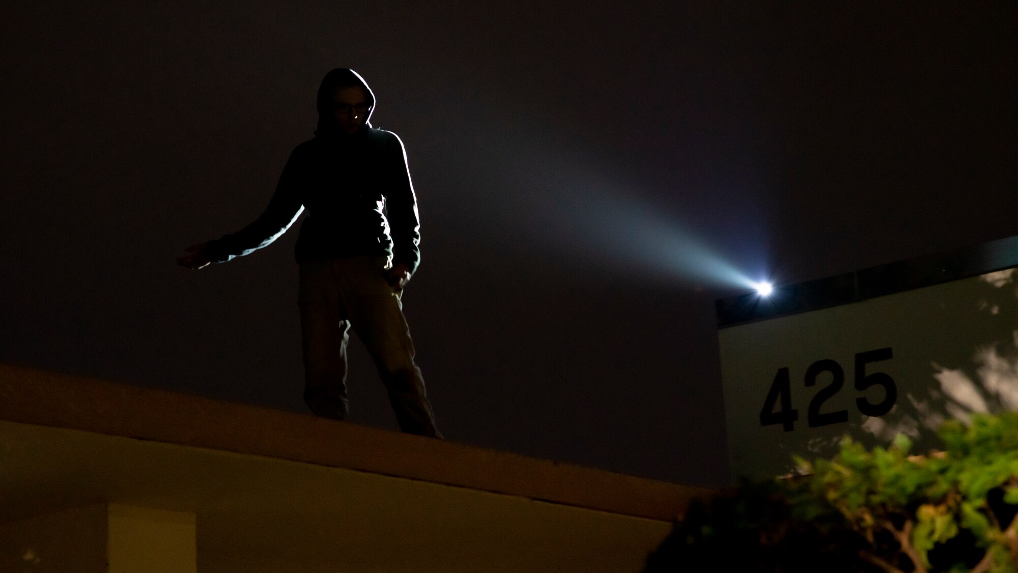 An airman stands atop a building simulating a hostile threat during training
