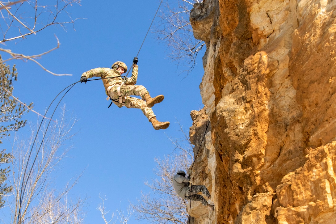 Two ROTC cadets rappel down a cliff.