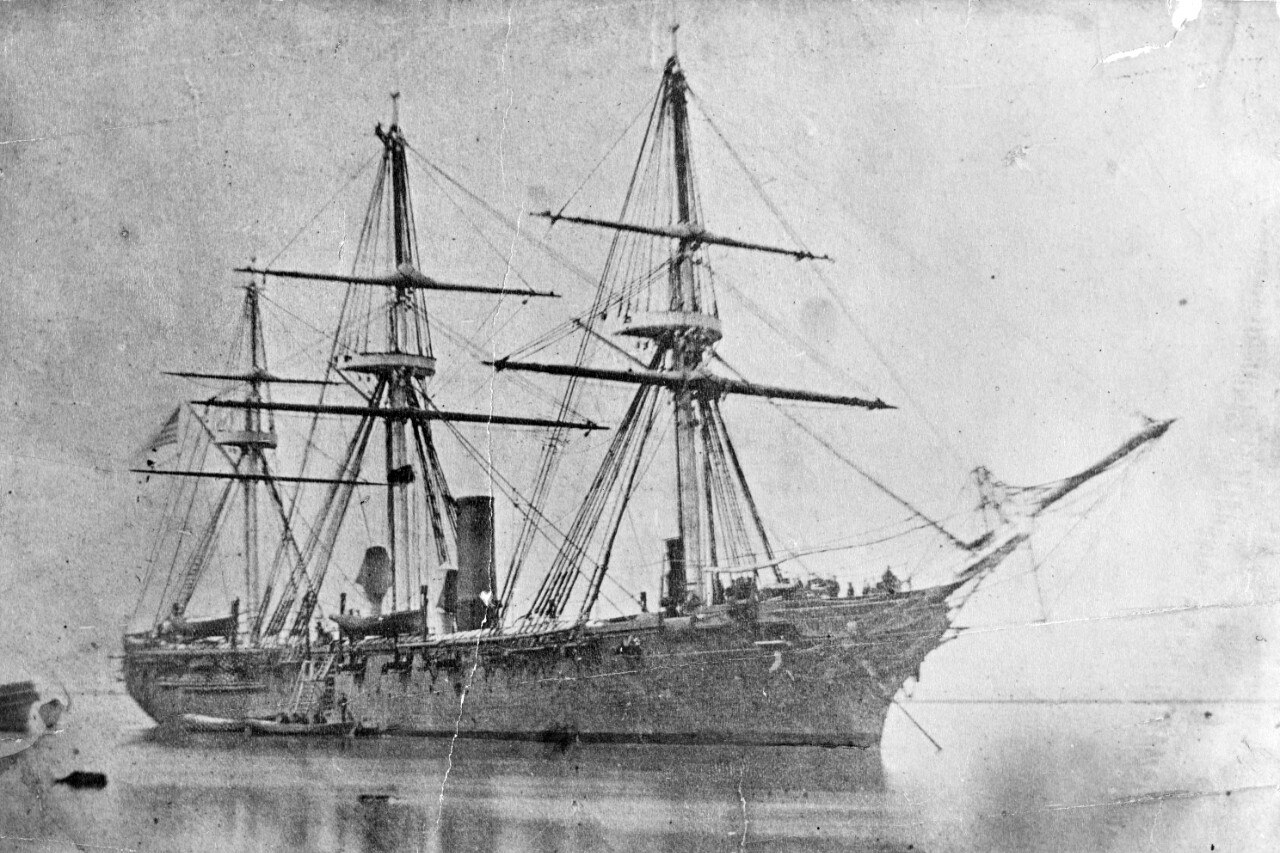 A large three-mast steamship sits in water.