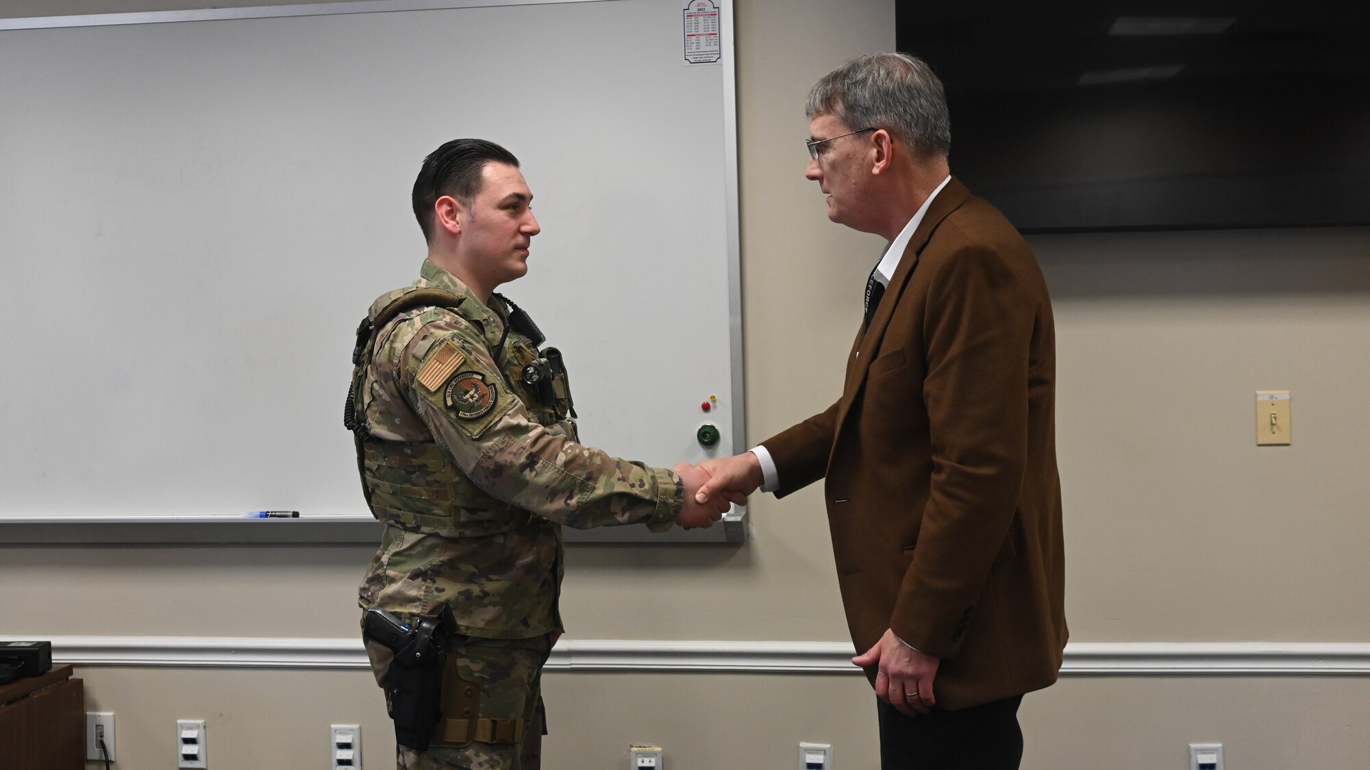U.S. Air Force Tech. Sgt. Cameron Lincoln, left, assistant flight chief assigned to the 175th Security Forces Squadron, is coined by Mr. Devin Cate, executive director, Air National Guard, March 5, 2022, during a visit to Warfield Air National Guard Base at Martin State Airport, Middle River, Maryland.  During his visit, Cate recognized numerous Airmen for their outstanding service during.  (U.S. Air National Guard photo by A1C Alexandra Huettner)