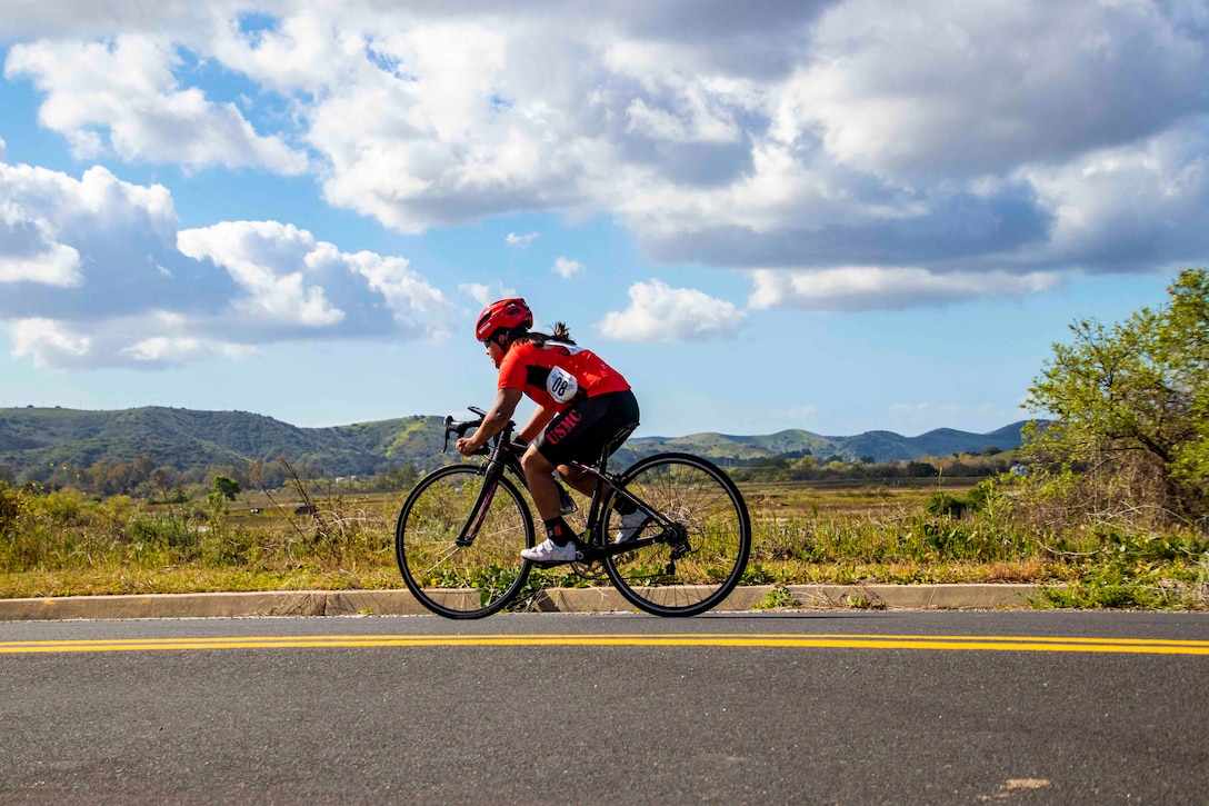 A Marine rides a bike down a road.