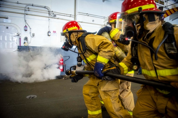 Sailors assigned to USS George H.W. Bush (CVN 77) fight a simulated fire in the hangar bay during Tailored Ship's Training Availability/Final Evaluation Problem (TSTA/FEP),