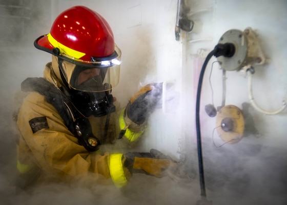 Damage Controlman 3rd Class Tyler Meimstorf, assigned to USS George H.W. Bush (CVN 77), opens the space to a simulated fire in the hangar bay during Tailored Ship's Training Availability/Final Evaluation Problem (TSTA/FEP),