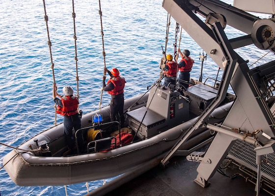 Sailors assigned to the aircraft carrier USS George H.W. Bush (CVN 77) lower into the ocean on a rigid-hull inflatable boat for small boat operations evaluated by Afloat Training Group during Tailored Ship's Training Availability/Final Evaluation Problem (TSTA/FEP),