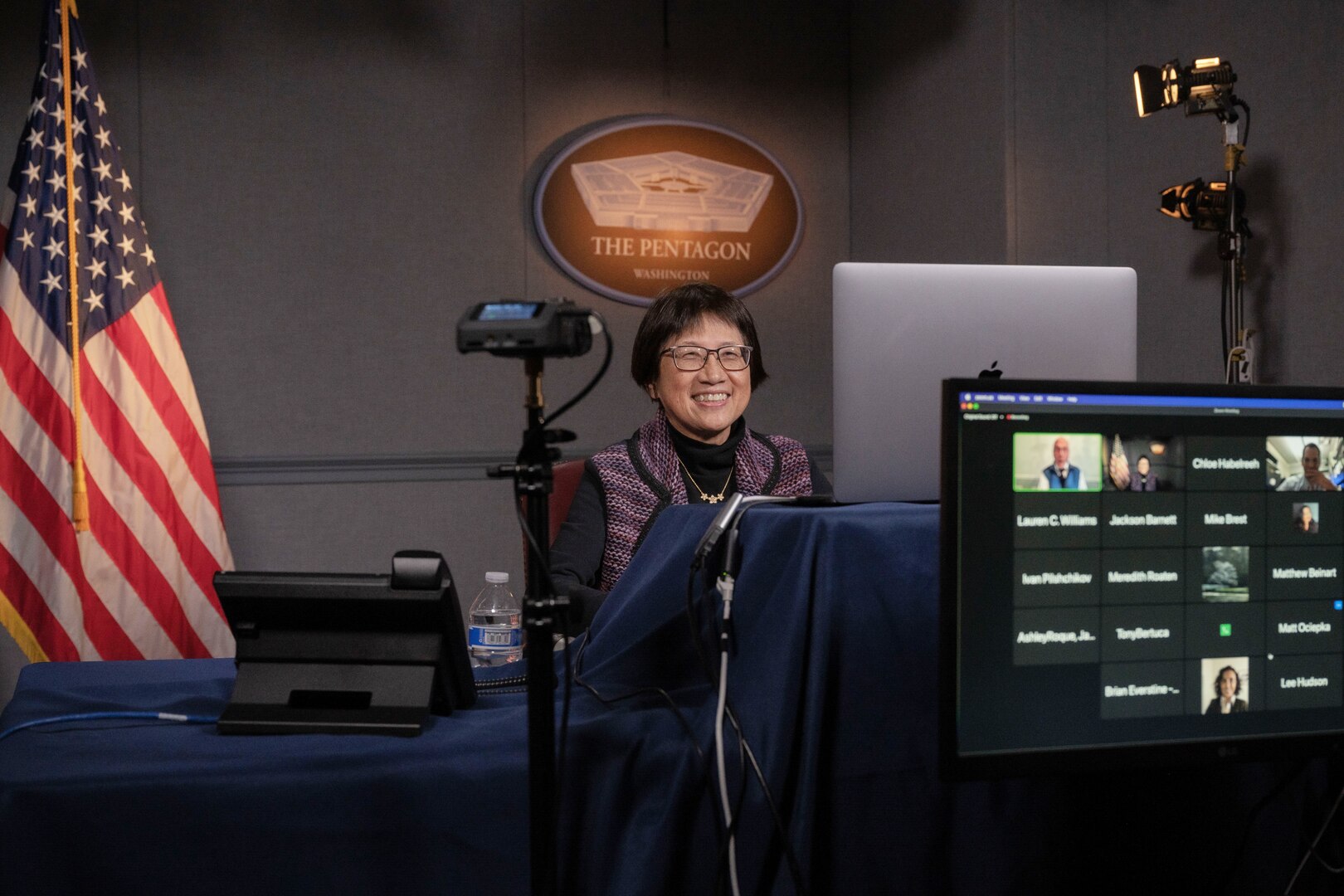 A woman is seated in front of a computer monitor.