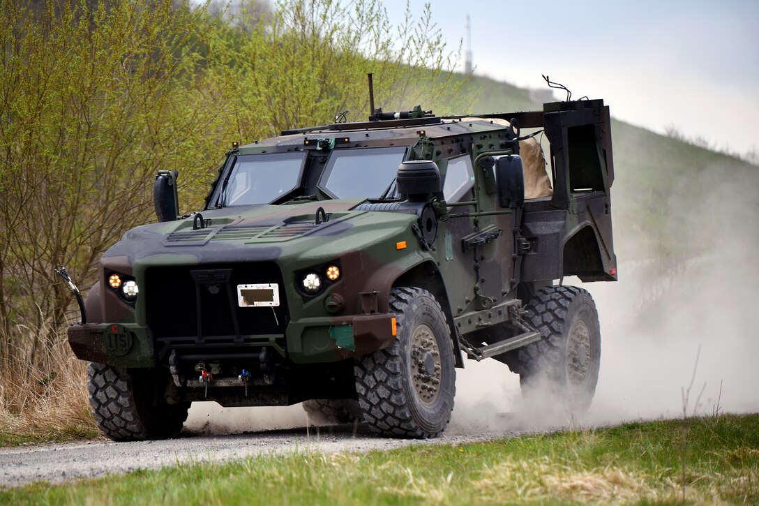 A combat vehicle drives down a dirt road.