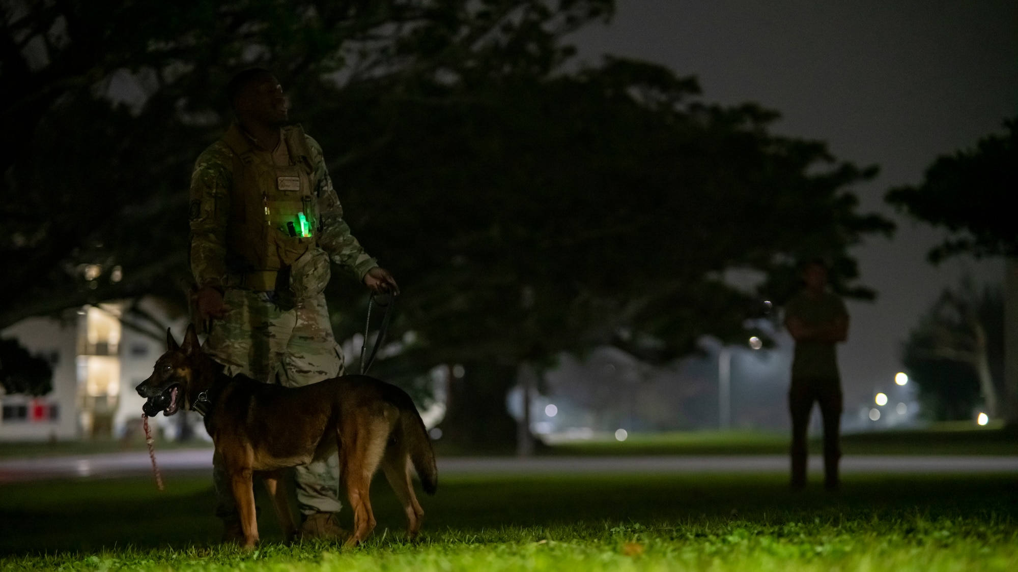 Military working dog trainer stands with his dog as he simulates de-escalating a hostile situation