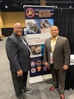 AJ Johnson and Rob Myles pose next to a sign for Office of Small Business Programs.