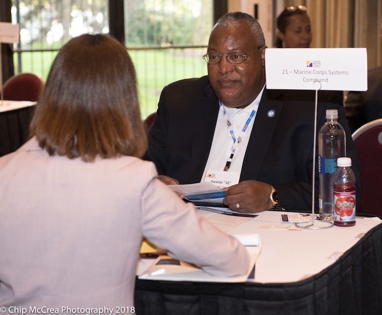 AJ Johnson sits at a table with a conference participant.