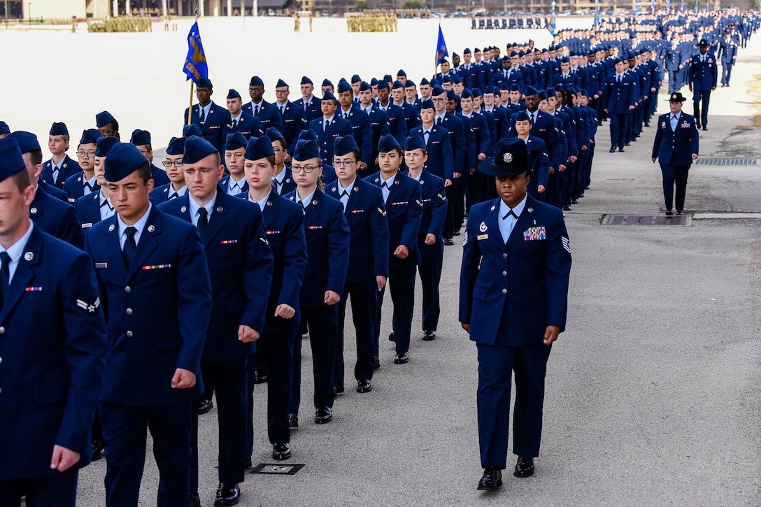 A very large group of men and women in uniform march in formation.