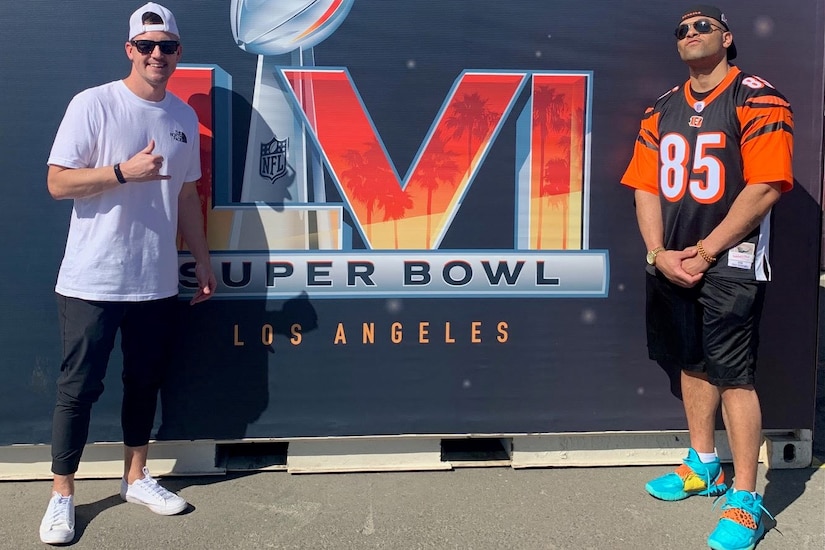Two men pose in front of an oversized “Super Bowl LVI” sign.