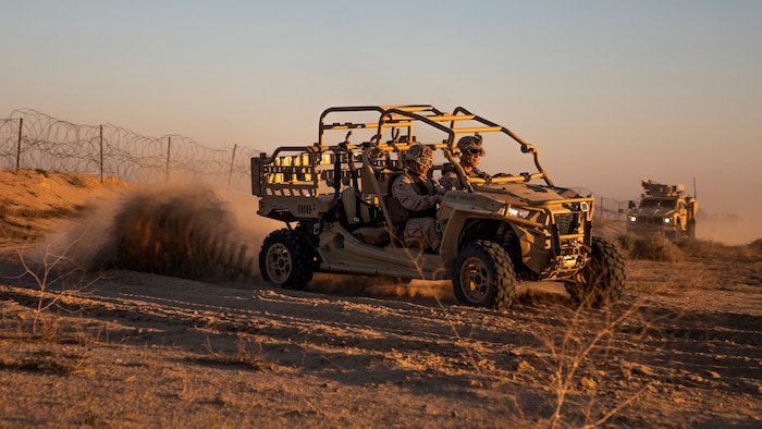 Two marines drive a Utility Task Vehicle (UTV)