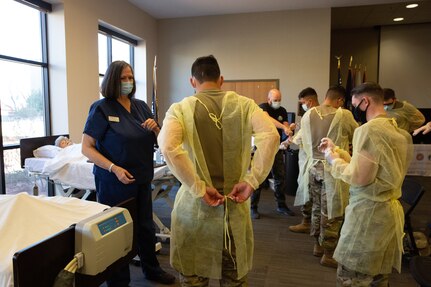 Soldiers learn the proper way to put on and take off personal protective gowns and gloves
