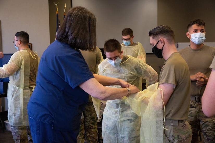 A nurse demonstrates how to put on personal protection garment.