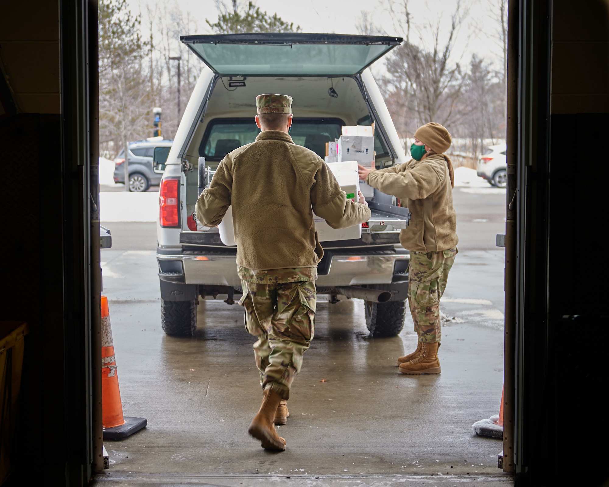 Photo of U.S. Air Force Airman 1st Class Christian Arildsen (left), a crew chief with the 158th Maintenance Squadron, Vermont Air National Guard, and Staff Sgt. Ivana Dober, an ammunitions specialist assigned to the 158th Maintenance Squadron, Vermont Air National Guard, loads up the final coolers used to transport COVID-19 test kits at a Vermont Department of Health lab in Vermont, Feb. 8, 2022.