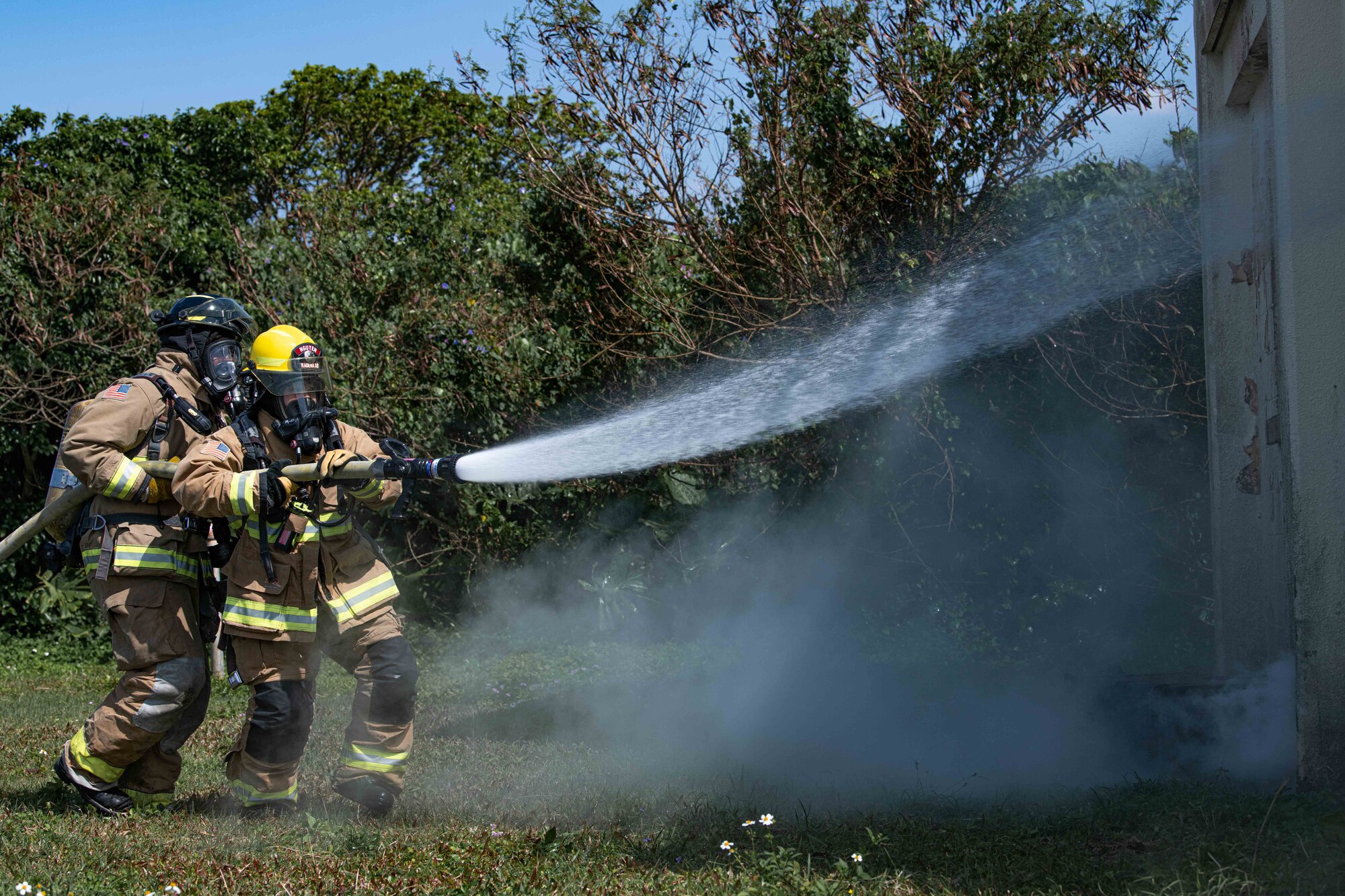 Firefighters spray water with a hose.