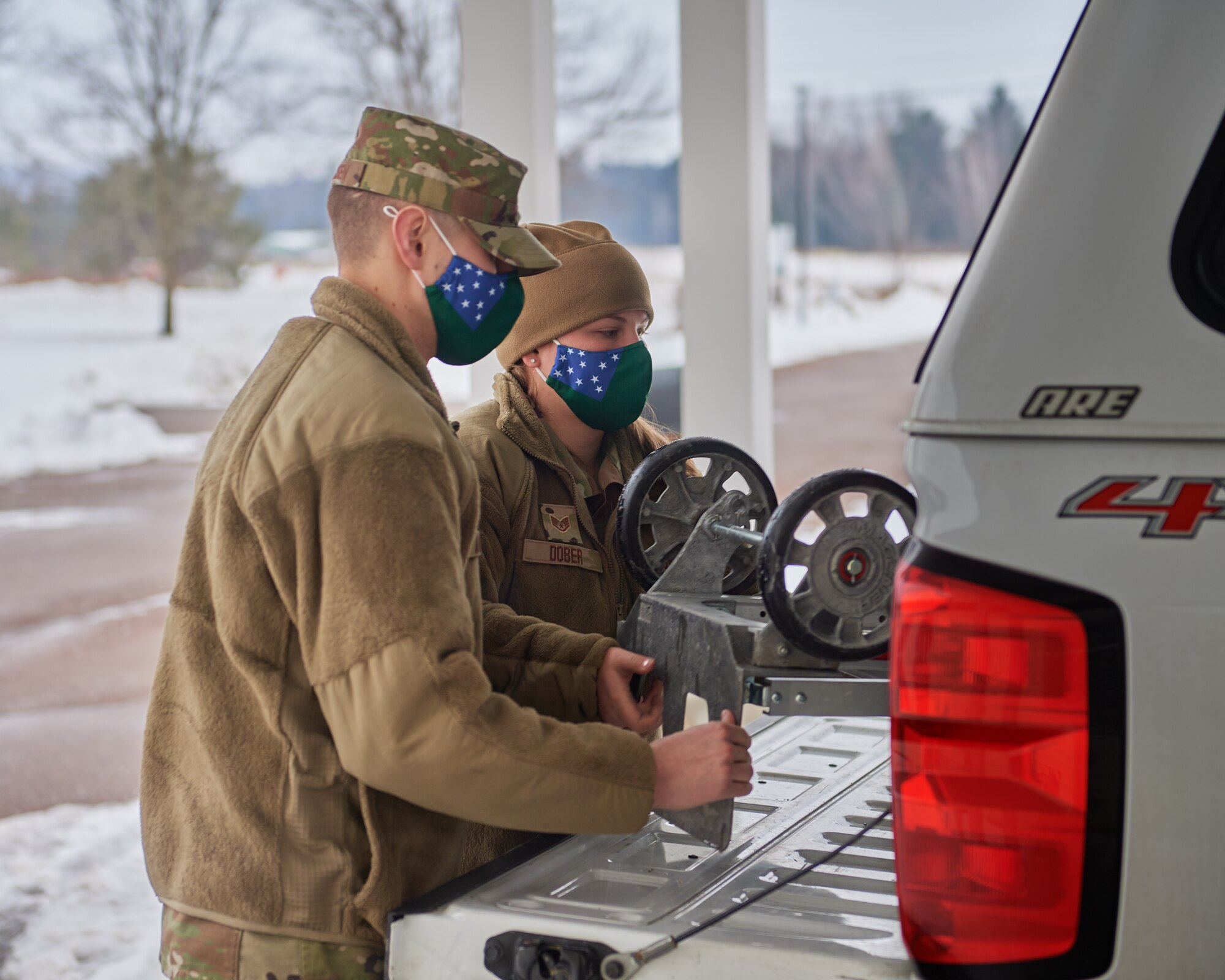 Photo of U.S. Air Force Airman 1st Class Christian Arildsen (left), a crew chief assigned to the 158th Maintenance Squadron, Vermont Air National Guard, and Staff Sgt. Ivana Dober, an ammunitions specialist assigned to the 158th Maintenance Squadron, Vermont Air National Guard, loads up a dolly after making a delivery of COVID-19 test kits to an assisted living facility in Vermont, Feb. 8, 2022.