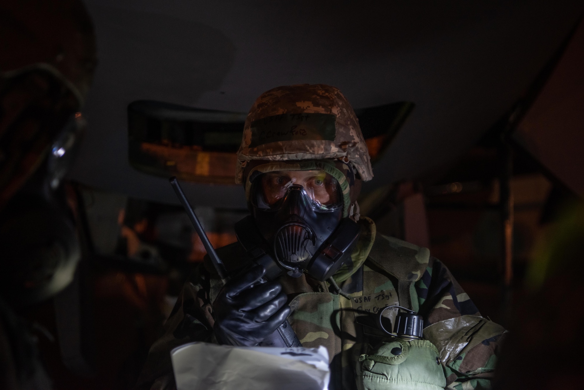 An Airman in protective gear uses a radio to communicate.
