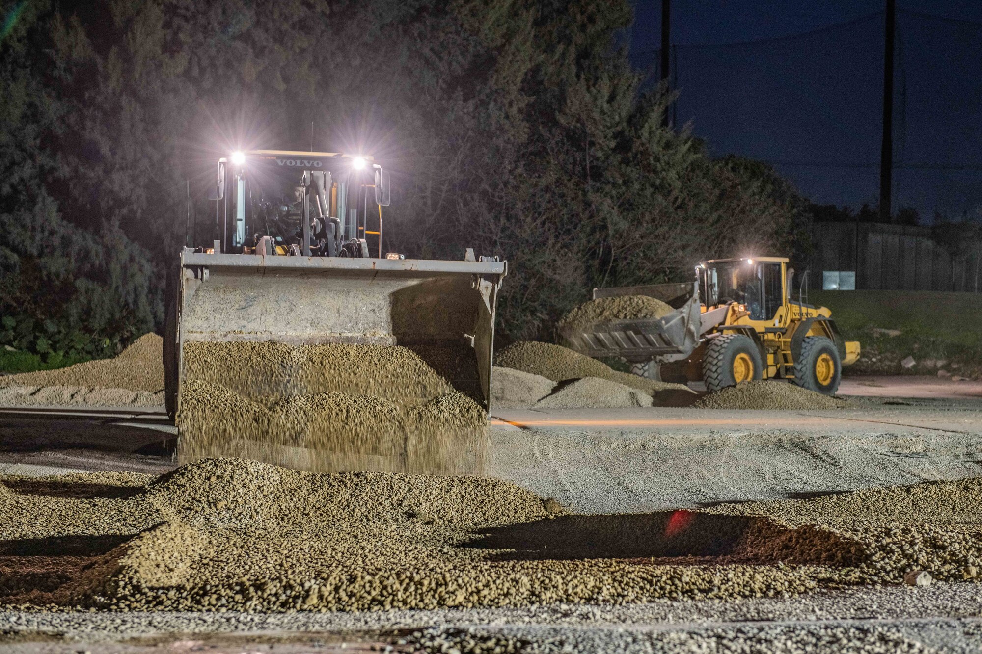 Two front end loaders transport gravel on a construction site