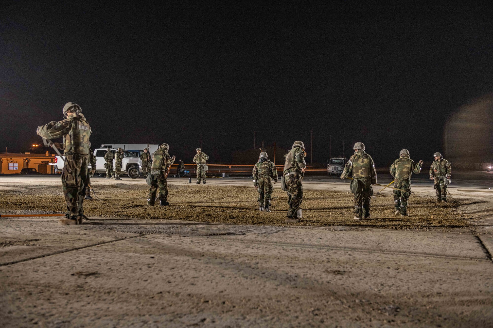 A bunch of Airmen rake and flatten fresh gravel