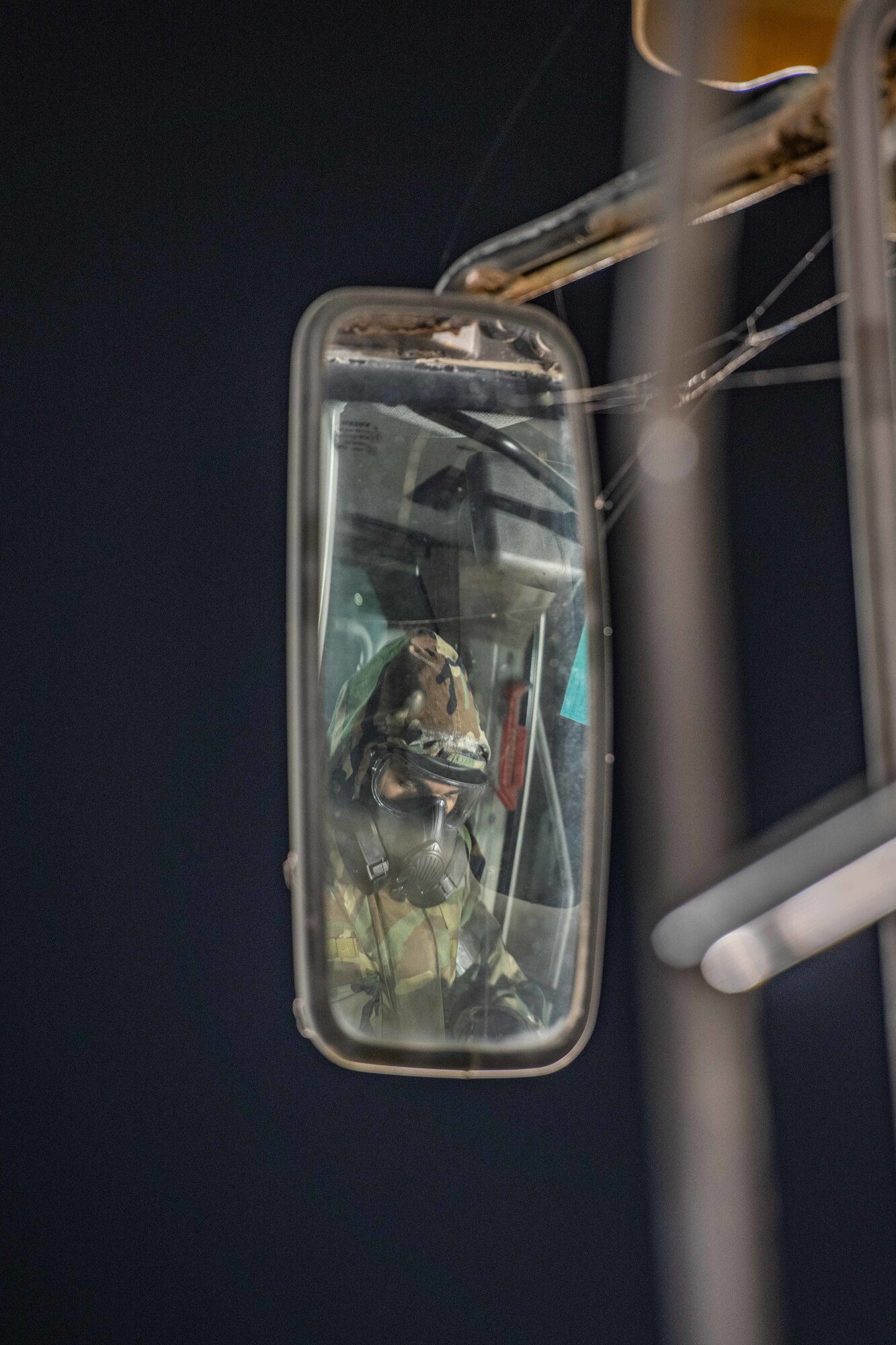 An Airman in a mirror looks at his gear through his mask