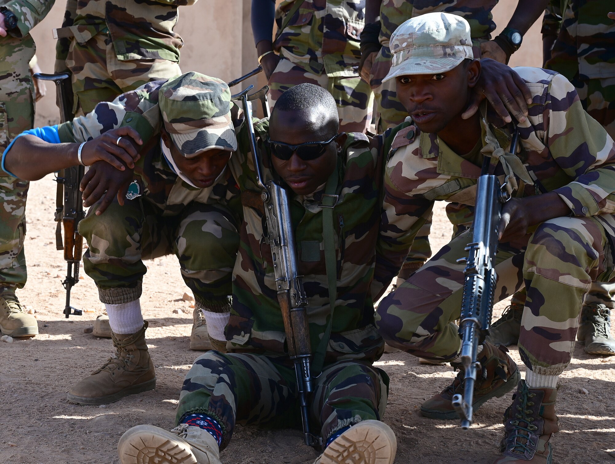 Three Nigerien Armed Forces (French language: Forces Armées Nigeriennes) members, practice a tactical carry taught to them by the 409th Expeditionary Security Forces Squadron air advisors and 724th Expeditionary Air Base Squadron firefighters  at Nigerien Air Base 201, Agadez, Niger, Jan. 21, 2022. The 409th ESFS hosted an eight-week course to train the FAN on various tactics such as combat lifesaving skills, weapon maneuvers, vehicle searches and patrol movements to counter the escalating violent extremism in the tri-border region of Niger, Burkina Faso, and Mali. (U.S. Air Force photo by Tech. Sgt. Stephanie Longoria)