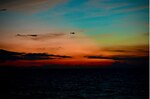 Coast Guard helicopter flies across colorful sunset