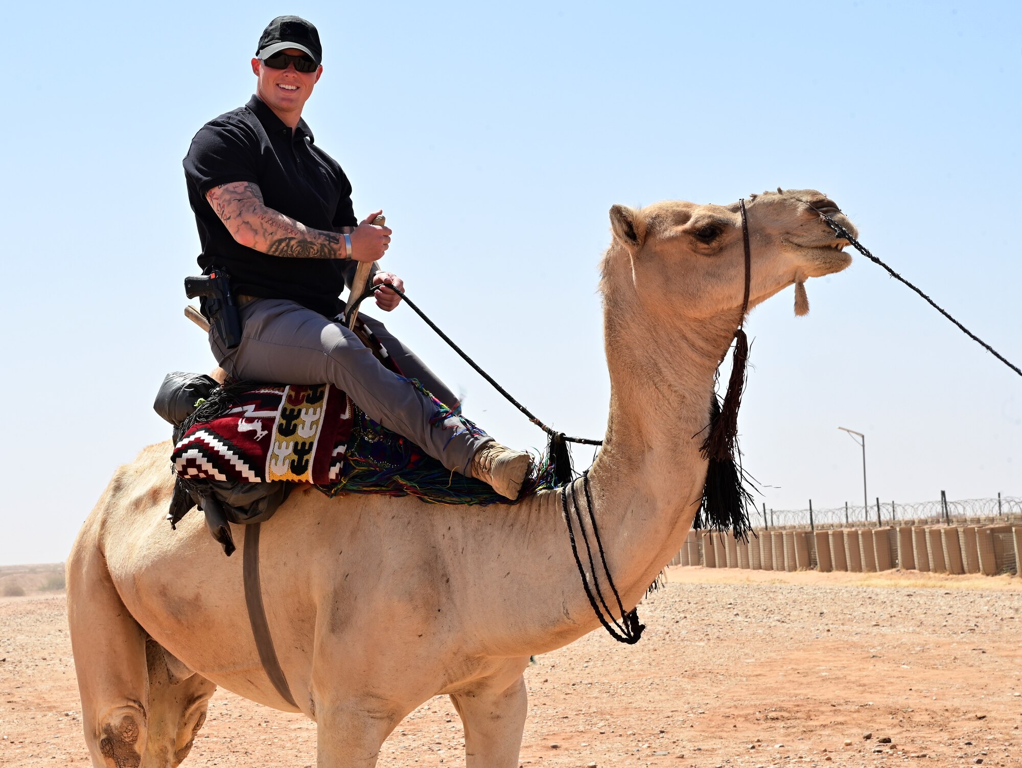 U.S. Air Force Airman 1st Class Brian Schmidt, 409th Expeditionary Security Forces Squadron member, rides a camel during a bazaar at Nigerien Air Base 201, Agadez, Niger, Feb. 27, 2022. Over 40 local vendors from the city of Agadez and surrounding villages attended the bazaar, selling various goods.  U.S. service members purchased approximately 10,532,000 West African CFA francs ($18K USD) worth of goods. Events like these enhance U.S., Niger relationships and stimulate local economic development. (U.S. Air Force photo by Tech. Sgt. Stephanie Longoria)