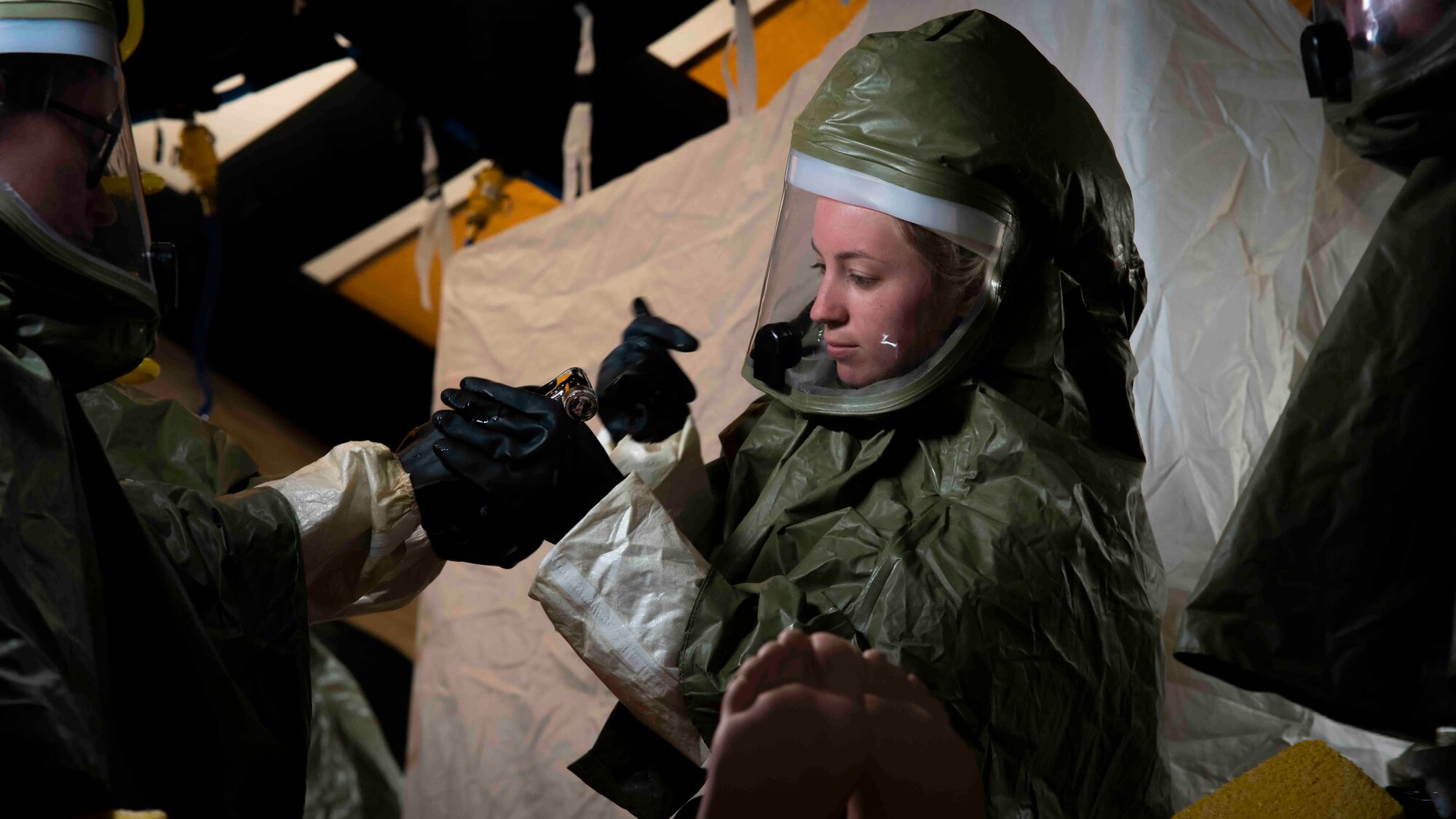 An Airman prepares to use a watering hose to spray down and decontaminate a simulated patient
