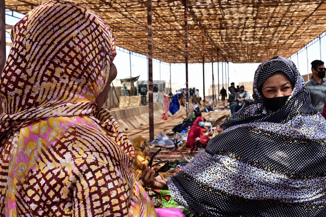 An airman tries on a traditional African dress at a market.