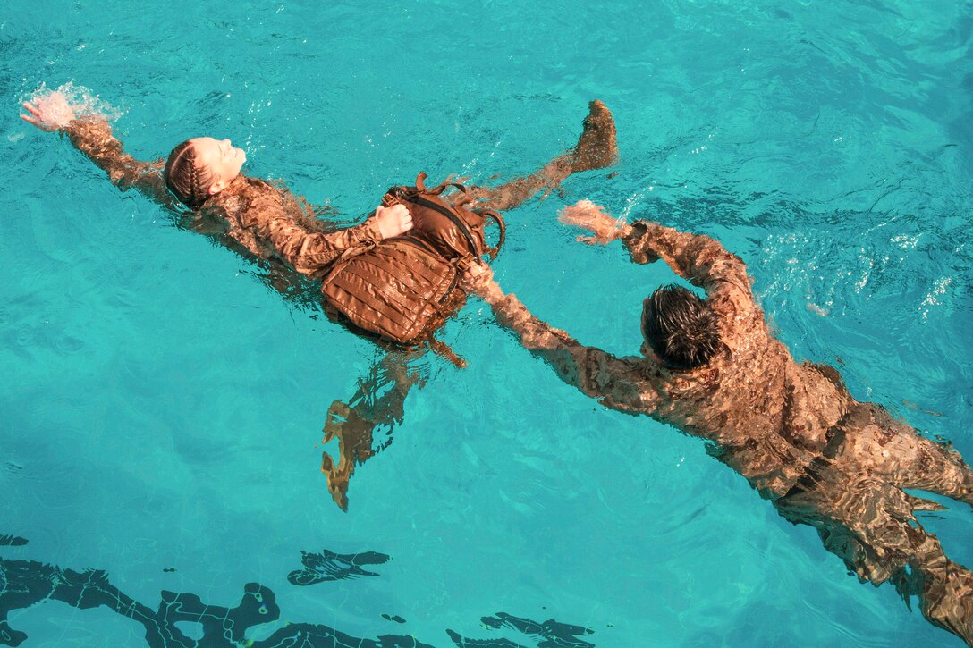 A Marine rescues a floating dummy during training in a pool.