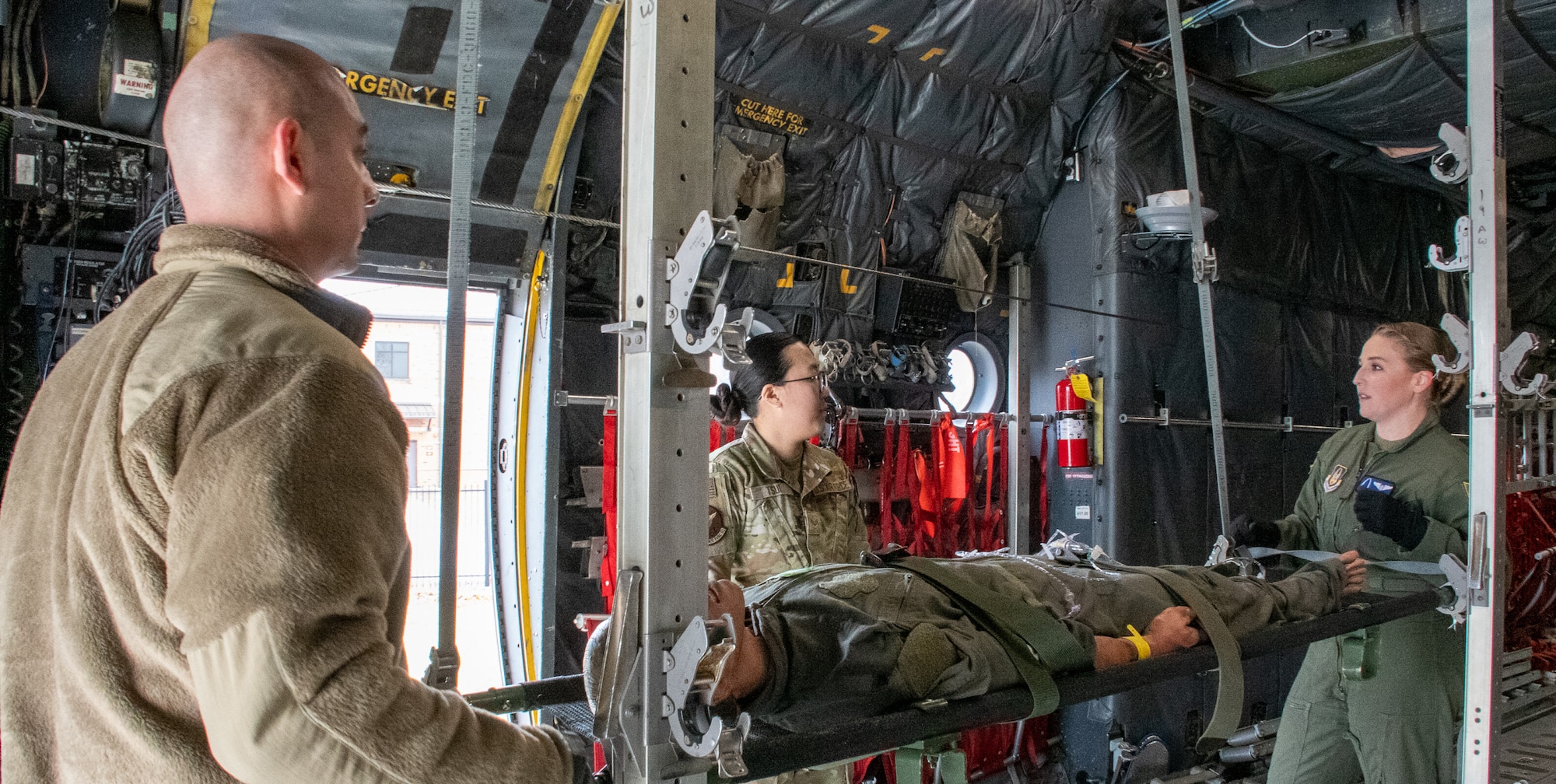 Senior Airman Katlyn Ledbetter and Master Sgt. Jose Gomez, Jr. instruct and mentor Senior Airman Tiffany Tsui on in-flight medical care procedures.