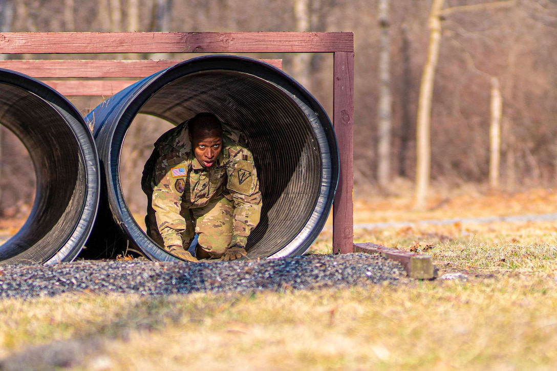 A soldier crawls through tubing.