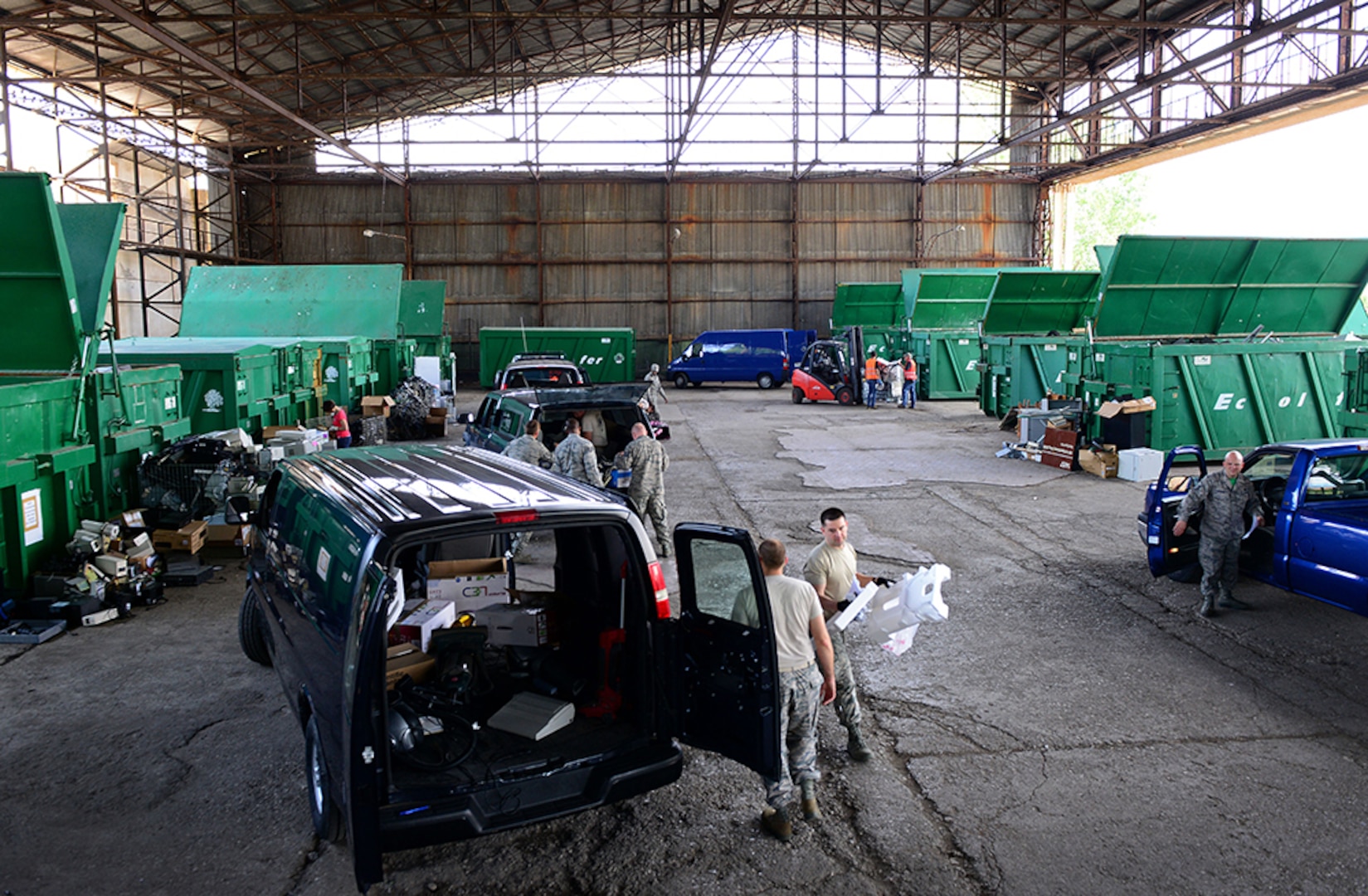 Airmen unload property from a van in a warehouse.