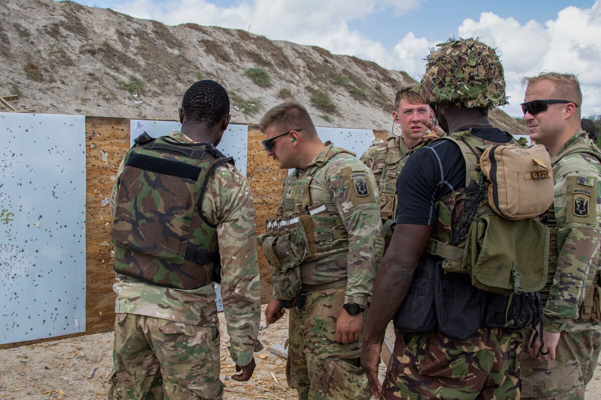 Multiple uniformed personnel stand near rifle targets.