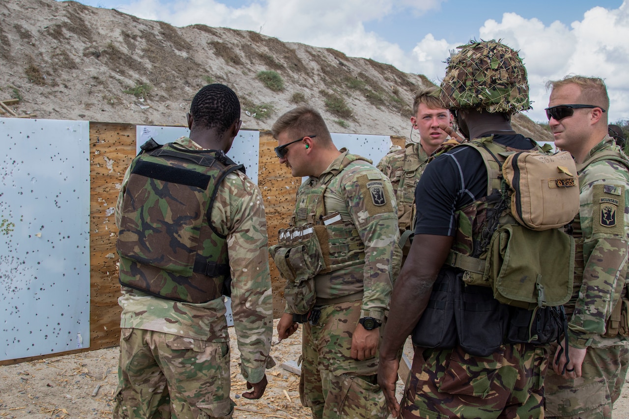 Multiple uniformed personnel stand near rifle targets.