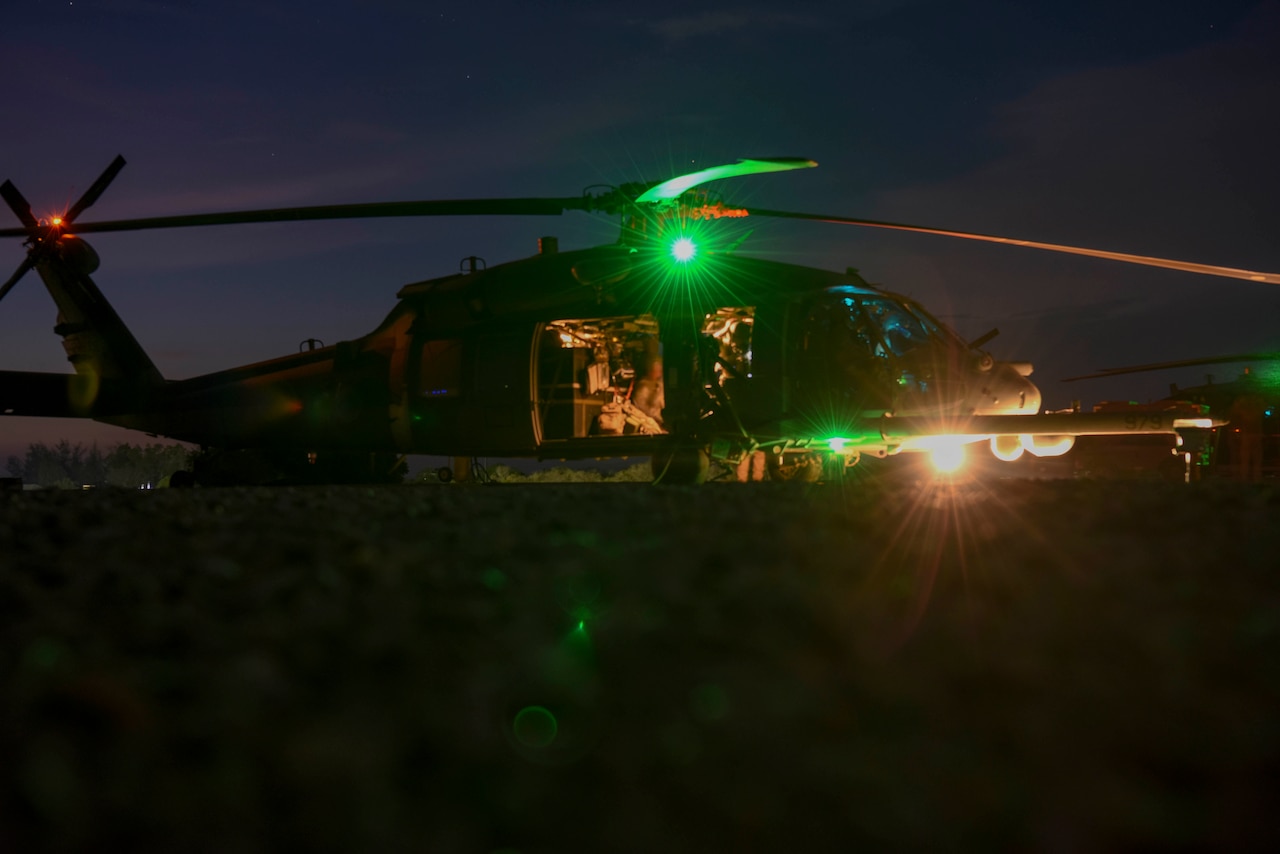 A helicopter sits on the ground at night.