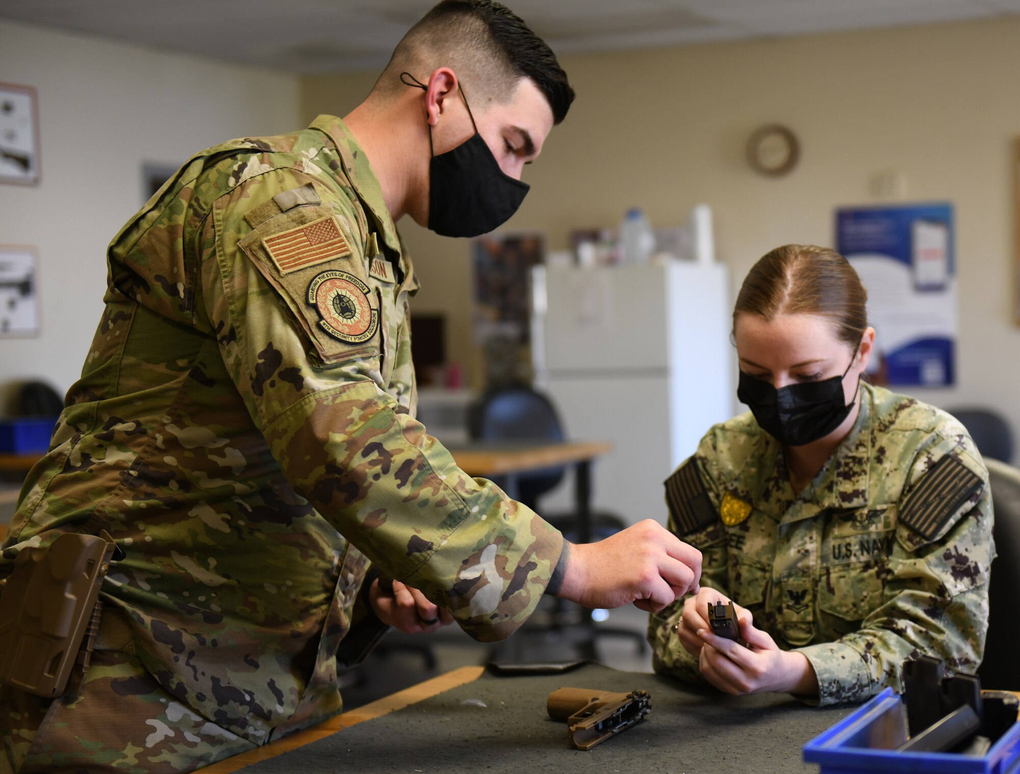 Staff Sgt. Garrett Mallison, 9th Security Forces Squadron combat arms instructor, left, explains the M18 modular handgun system components to Master-at-Arms 2nd Class Jordan McGee, VQ-3 Detachment, Feb. 28, 2022, at Beale Air Force Base, California.