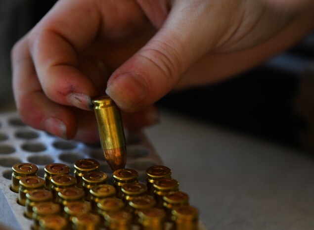 Master-at-Arms 2nd Class Jordan McGee, VQ-3 Detachment, picks up an M18 modular handgun system 9mm round Feb. 28, 2022, at Beale Air Force Base, California.